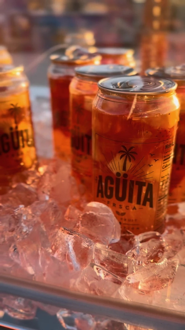 Fruit-filled Agüita FRSCA cans on ice in warm sunset light