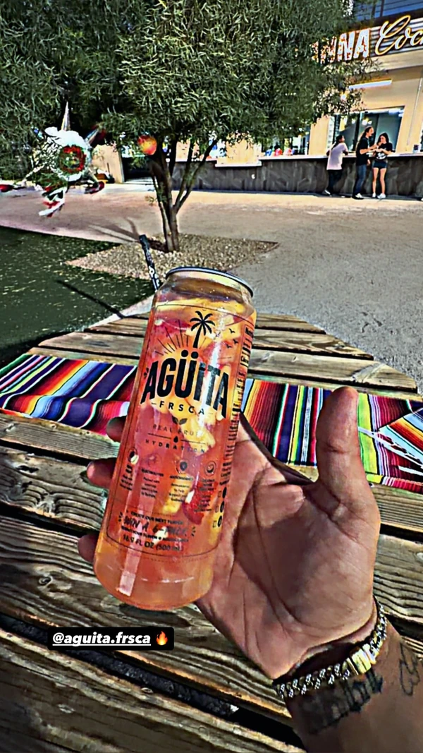 An Agüita FRSCA drink held beside a colorful serape at a Las Vegas gathering